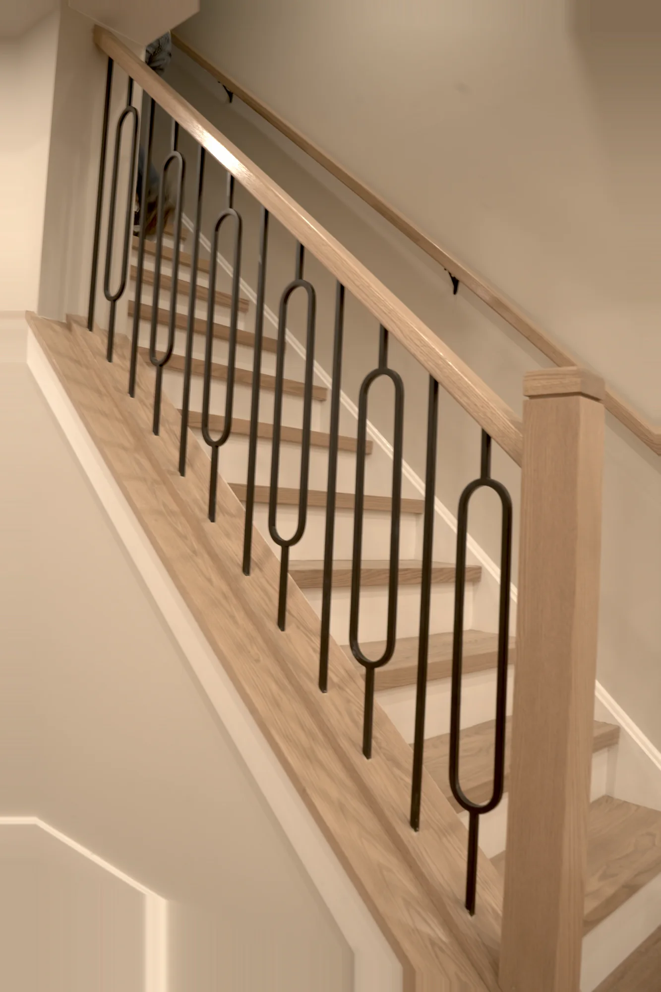 Basement staircase with wood handrail and iron balusters